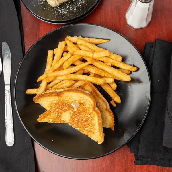 A grilled cheese sandwich with a side of golden french fries on a black plate.