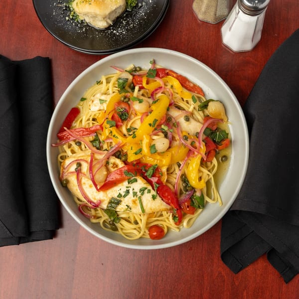 Capo & Co. pasta dish with chicken, colorful bell peppers, red onions, and cherry tomatoes.