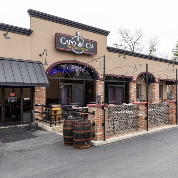 Exterior of Capo & Co. restaurant with a patio, brick accents, and string lights.