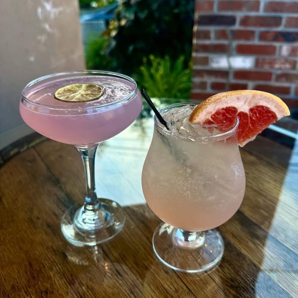 Two refreshing cocktails, one pink with a lime, the other light pink with a grapefruit slice.