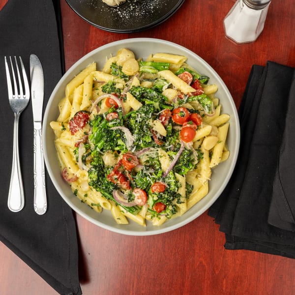 Penne pasta with broccoli, cherry tomatoes, red onion, and parmesan cheese in a cream sauce.